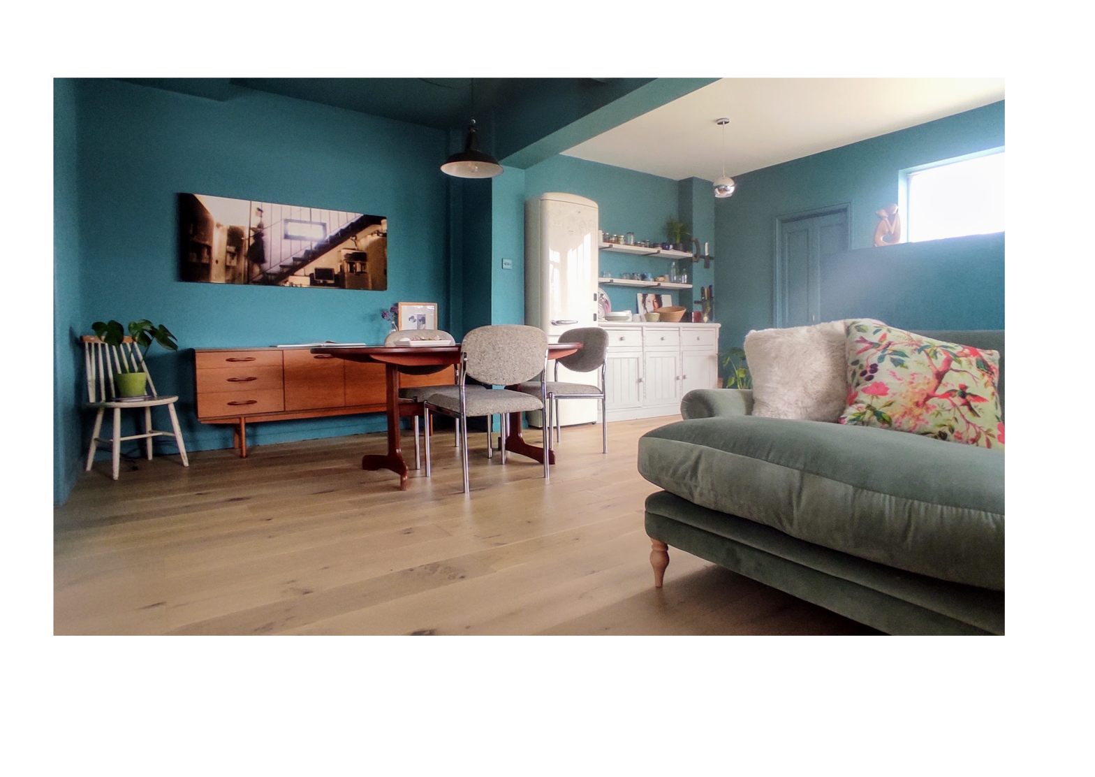 Contemporary living room remodel. Open plan kitchen and living room with monochrome teal walls and vintage G-Plan side board