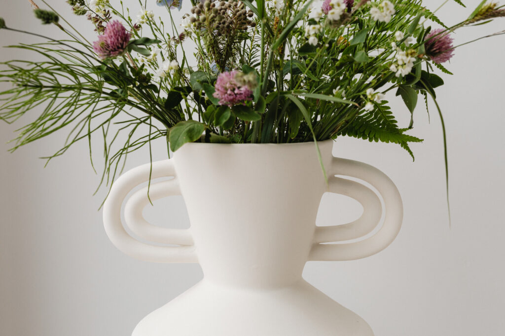 White ceramic vase with an arrangement of wildflowers