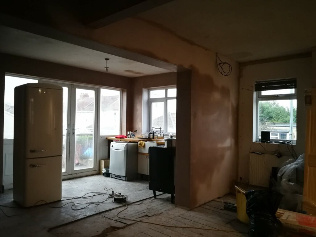 Renovation works in a kitchen. White goods are in place, walls are plastered and about to dry.