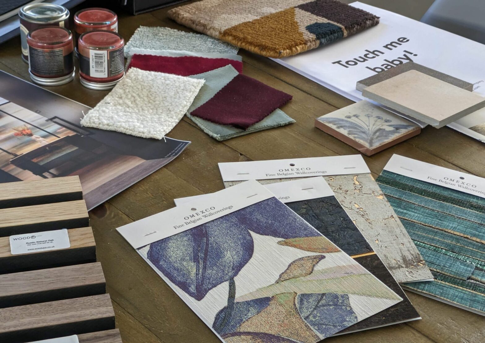 Samples of floral wallpaper, decorative wooden panels, paint pots, contemporary rug